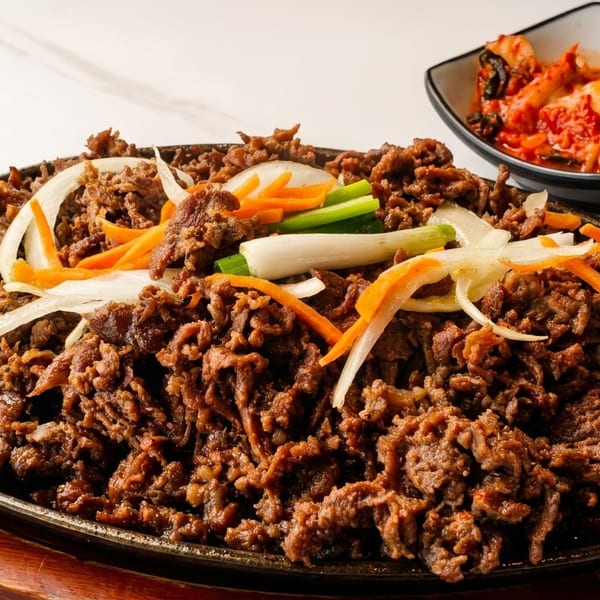 Sizzling bulgogi with onions, carrots, and scallions, served with a side of kimchi.